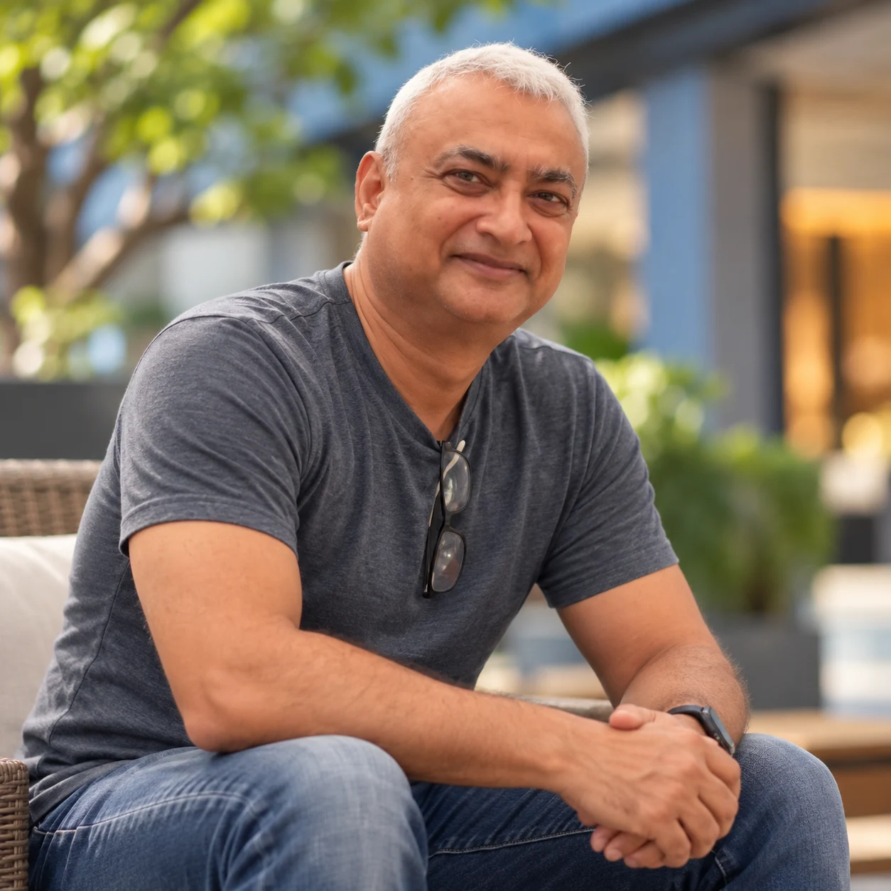 Absteq Consulting’s founder seated in a warm courtyard, with glasses hanging from his shirt.